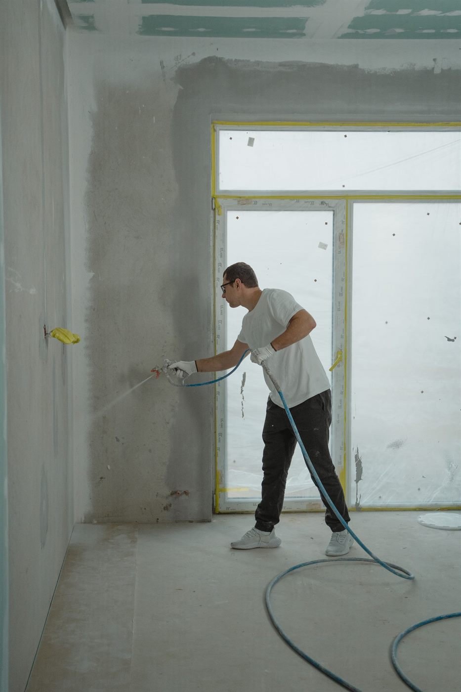 Vakman spuit een wand met een spuitinstallatie