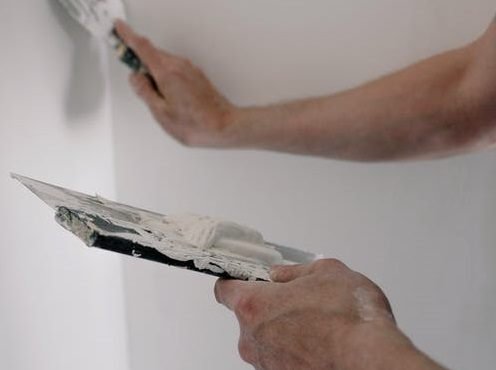 Stukadoor werkt een wand glad af met een spaan